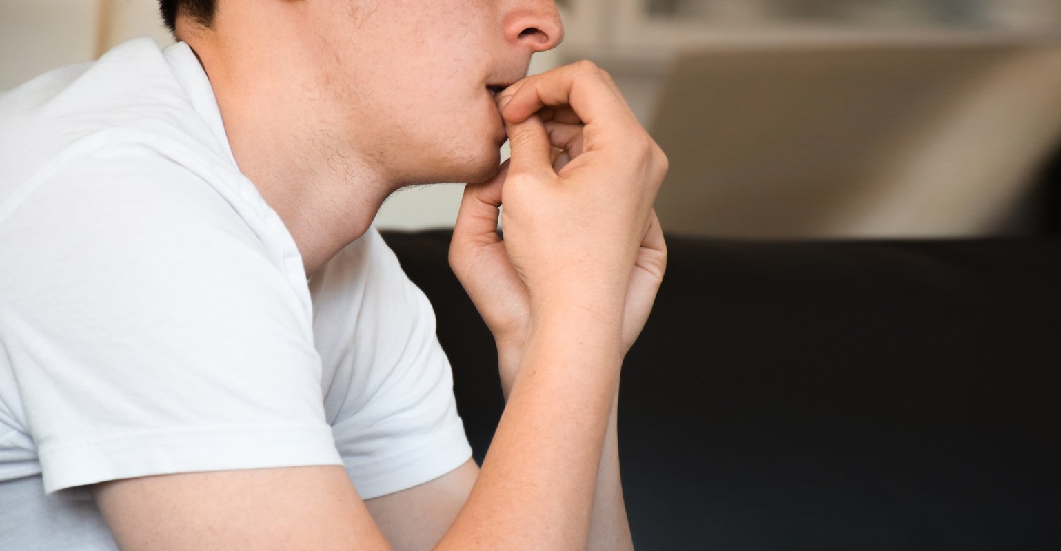 Young man feeling anxious and nervous biting nails